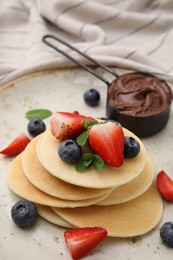 Photo of Delicious pancakes with berries and chocolate spread on plate, closeup