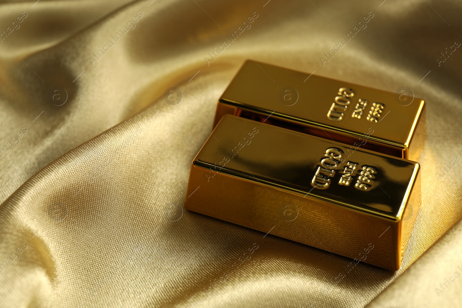 Photo of Gold bars on shiny silk fabric, space for text