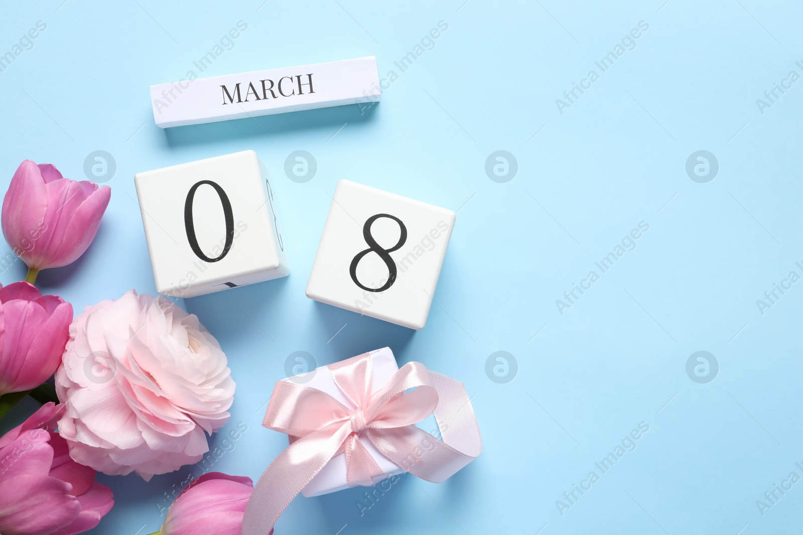 Photo of International Women's day - 8th of March. Gift box, wooden block calendar, beautiful flowers and space for text on light blue background, flat lay