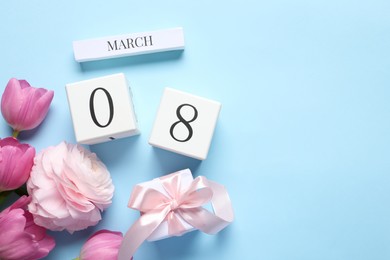 Photo of International Women's day - 8th of March. Gift box, wooden block calendar, beautiful flowers and space for text on light blue background, flat lay