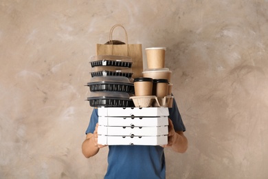 Courier with stack of orders on beige background. Food delivery service