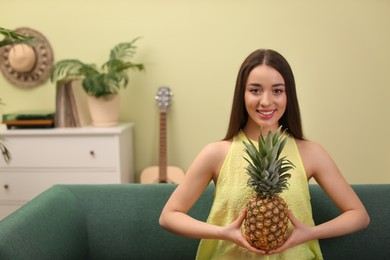 Young woman with fresh pineapple at home, space for text. Exotic fruit