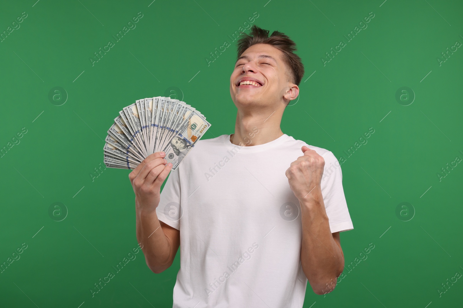 Photo of Happy man with dollar banknotes on green background