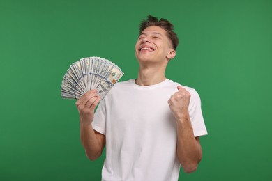 Happy man with dollar banknotes on green background