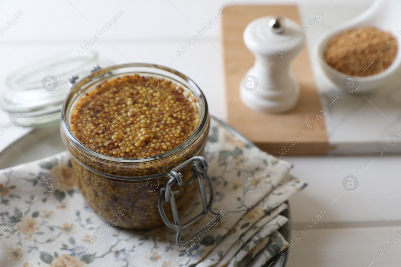 Photo of Jar of whole grain mustard on white wooden table. Space for text