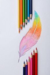 Drawing of feather and colorful pencils on white background, top view