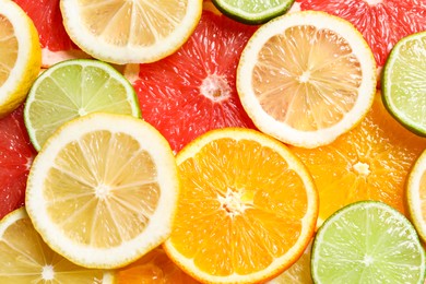 Photo of Different sliced citrus fruits as background, top view