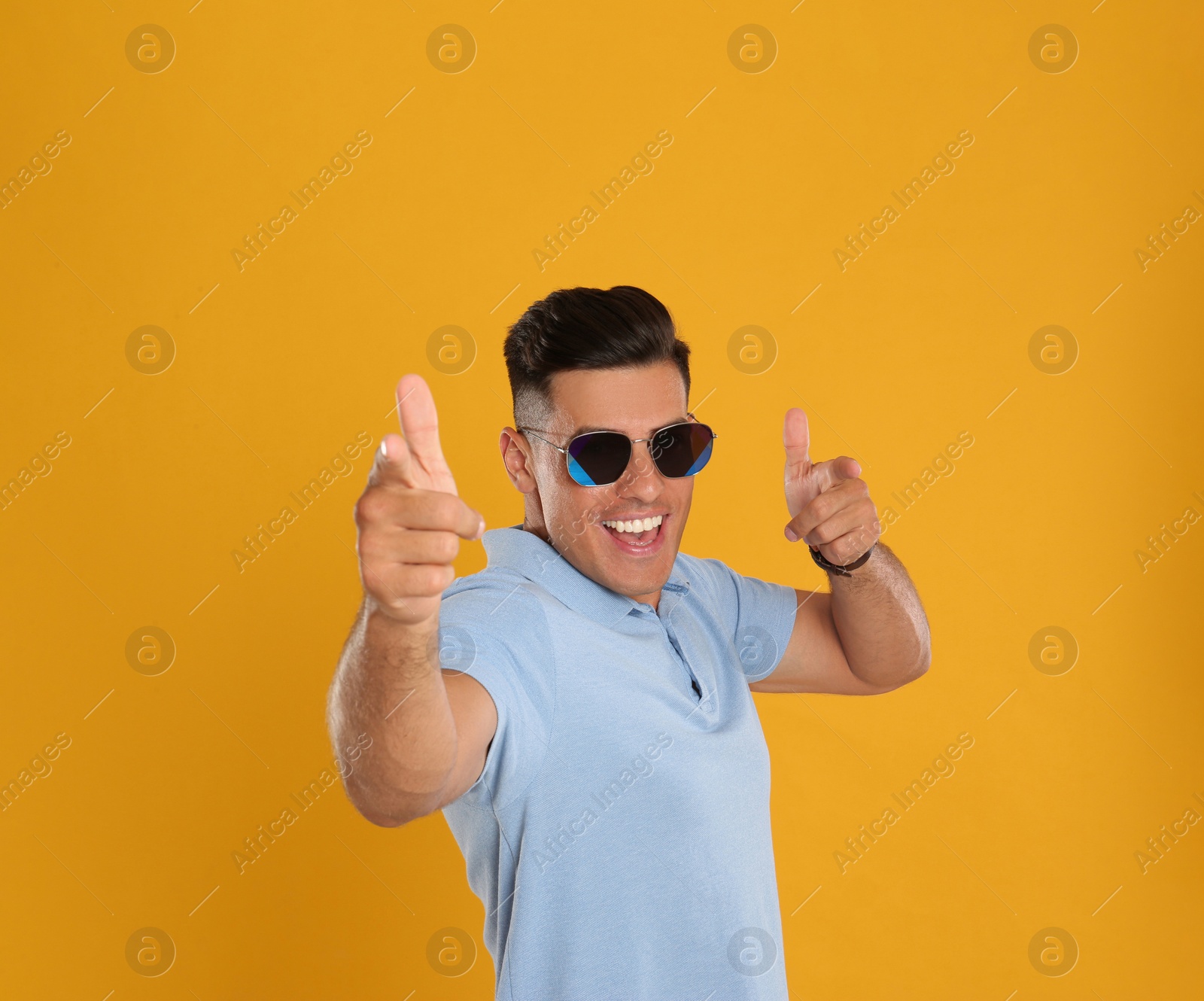 Photo of Excited man wearing sunglasses on yellow background