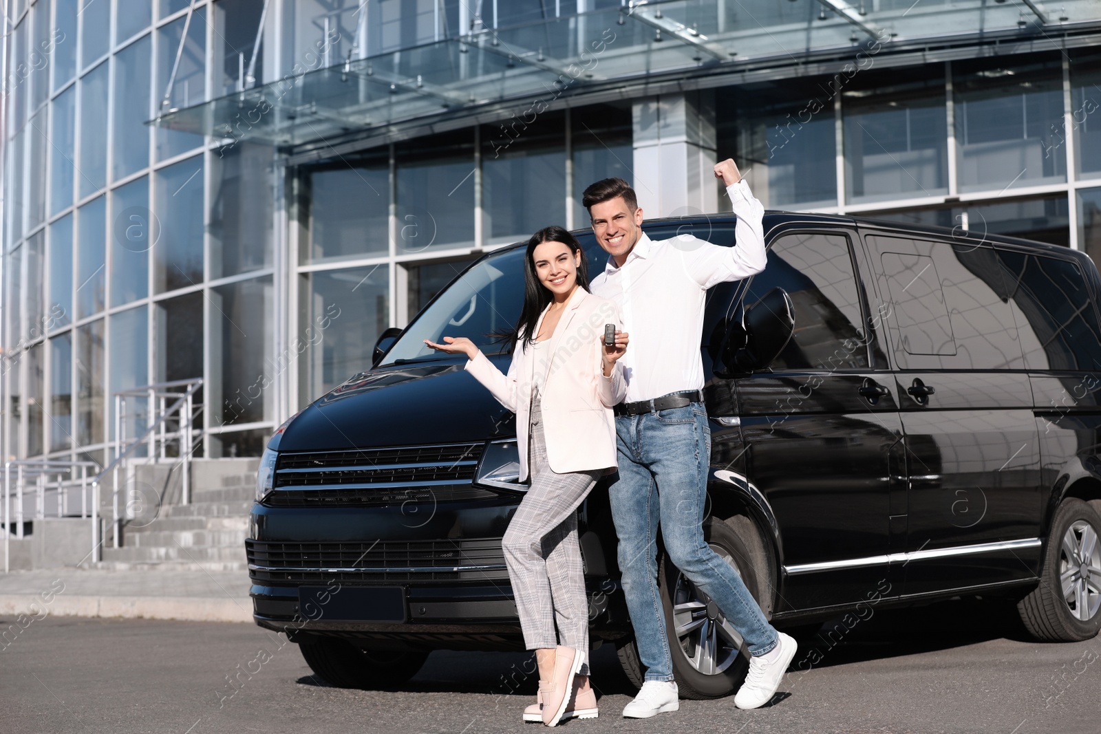 Photo of Happy couple with key near car on city street. Buying new auto