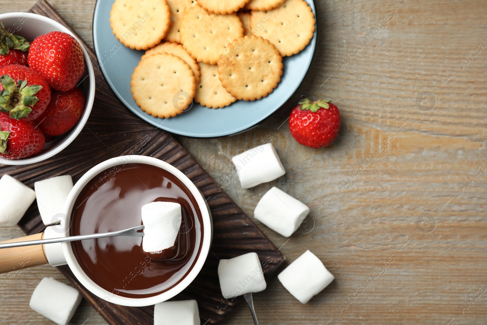 Photo of Flat lay composition with pot of chocolate fondue and marshmallow on wooden table