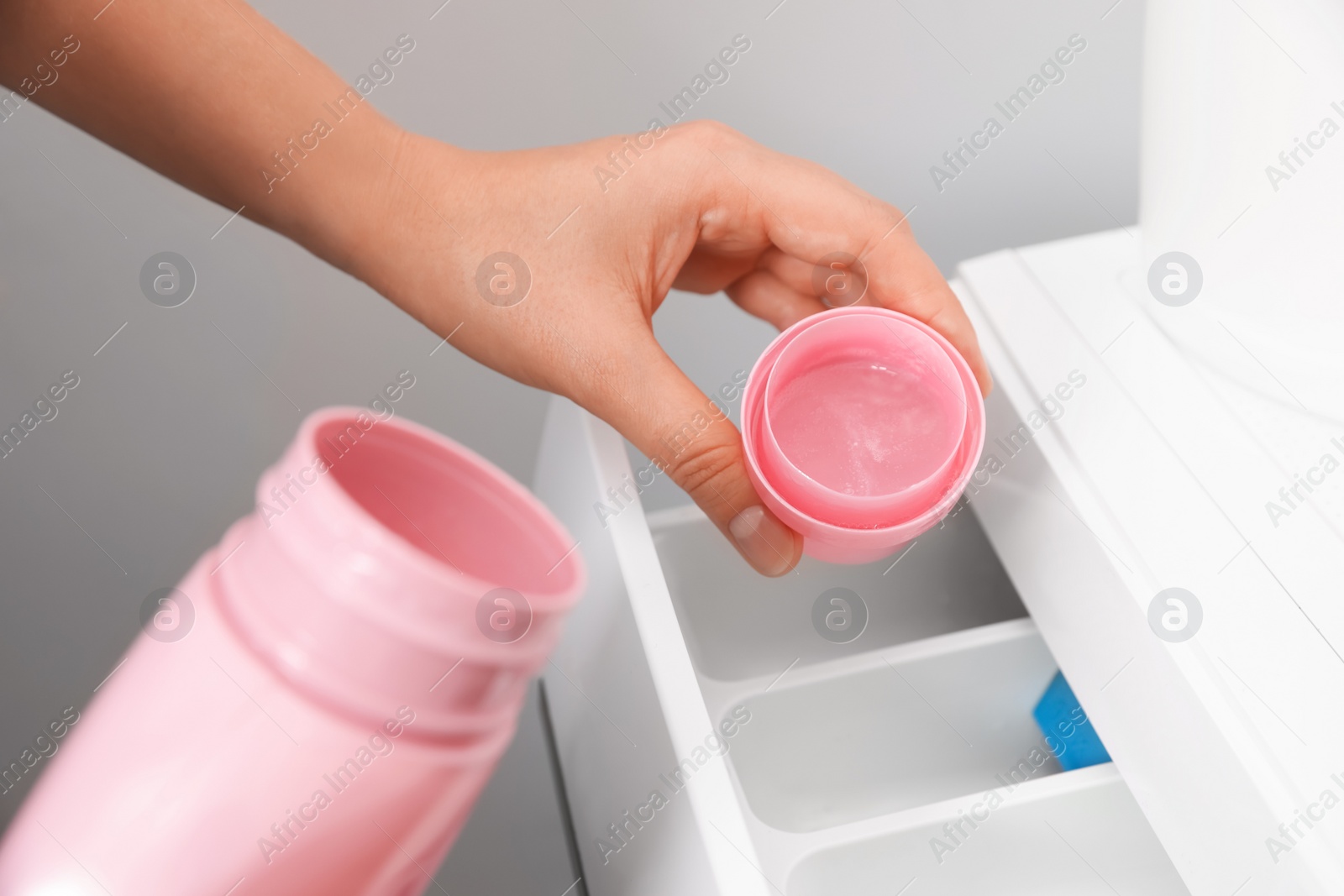 Photo of Woman pouring laundry detergent into drawer of washing machine, closeup