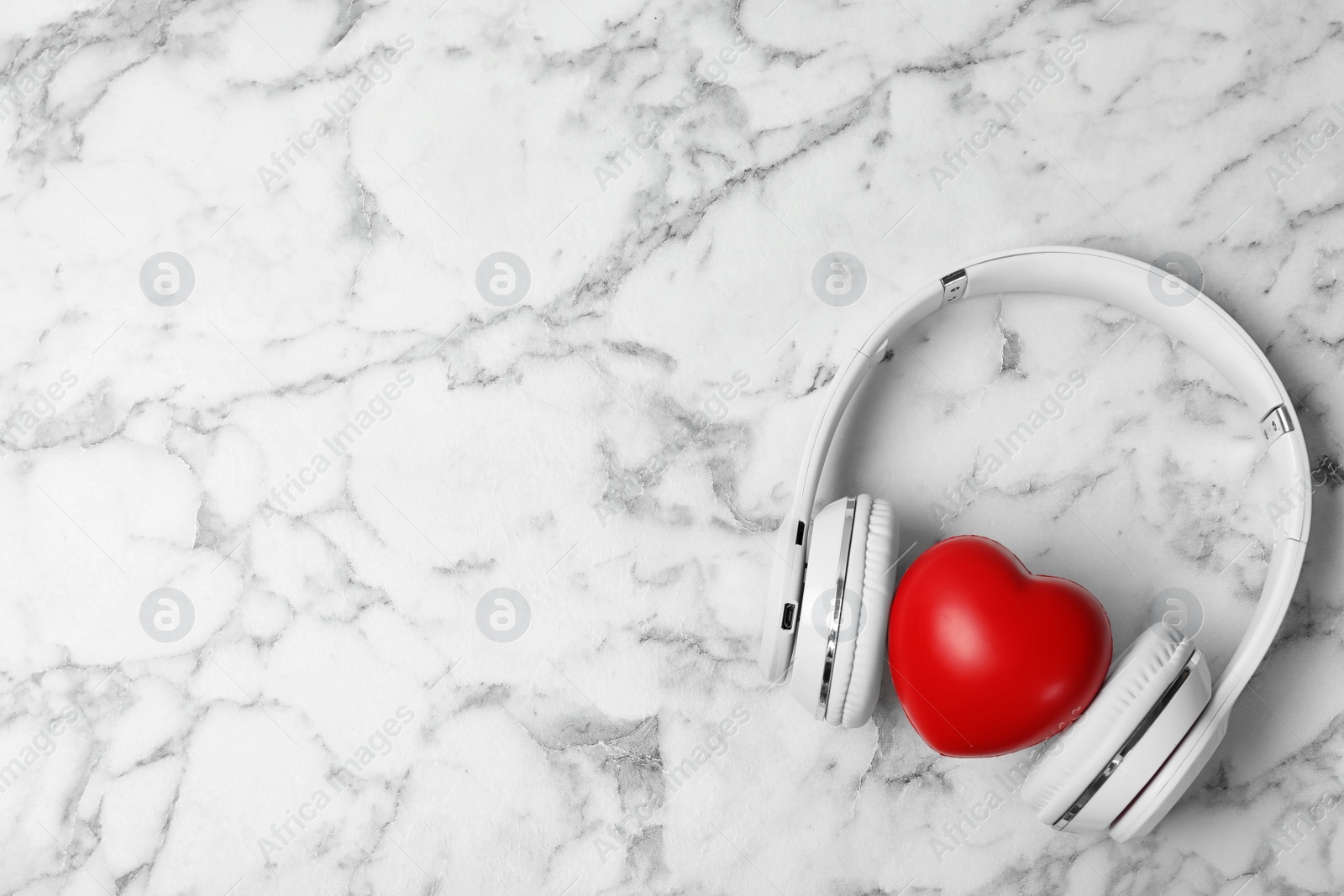 Photo of Headphones, heart and space for text on marble background, top view