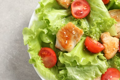 Delicious salad with chicken and cherry tomato on light grey table, top view