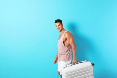 Photo of Young man with suitcase on color background. Space for text