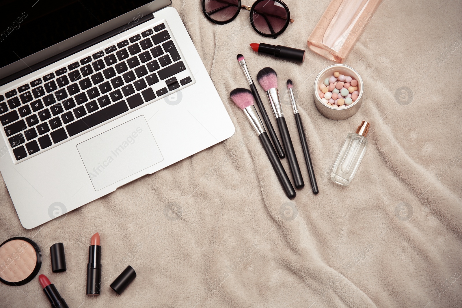 Photo of Flat lay composition with laptop and makeup products for woman on fabric