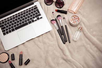 Flat lay composition with laptop and makeup products for woman on fabric