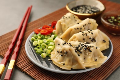 Delicious gyoza (asian dumplings) with sesame seeds, green onions and chopsticks on table, closeup