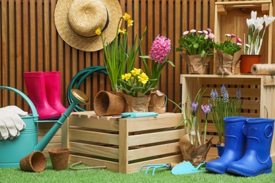 Composition with different gardening tools on artificial grass at wooden wall