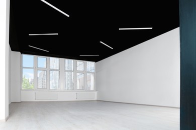 Photo of Empty office room with black ceiling and clean windows. Interior design