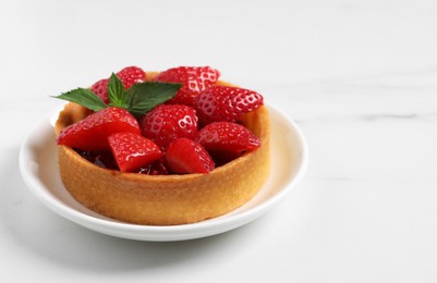 Photo of Tartlet with fresh strawberries on white marble table, closeup and space for text. Delicious dessert