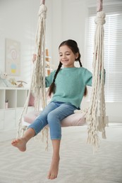 Photo of Cute little girl playing on swing at home