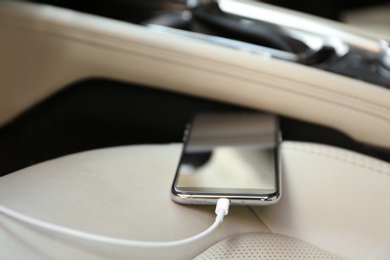 Mobile phone with charging cable in car, closeup