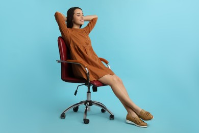 Photo of Young woman relaxing in comfortable office chair on turquoise background