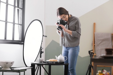 Photo of Young woman with professional camera taking food photo in studio