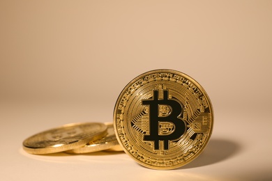 Shiny gold bitcoins on beige background. Digital currency