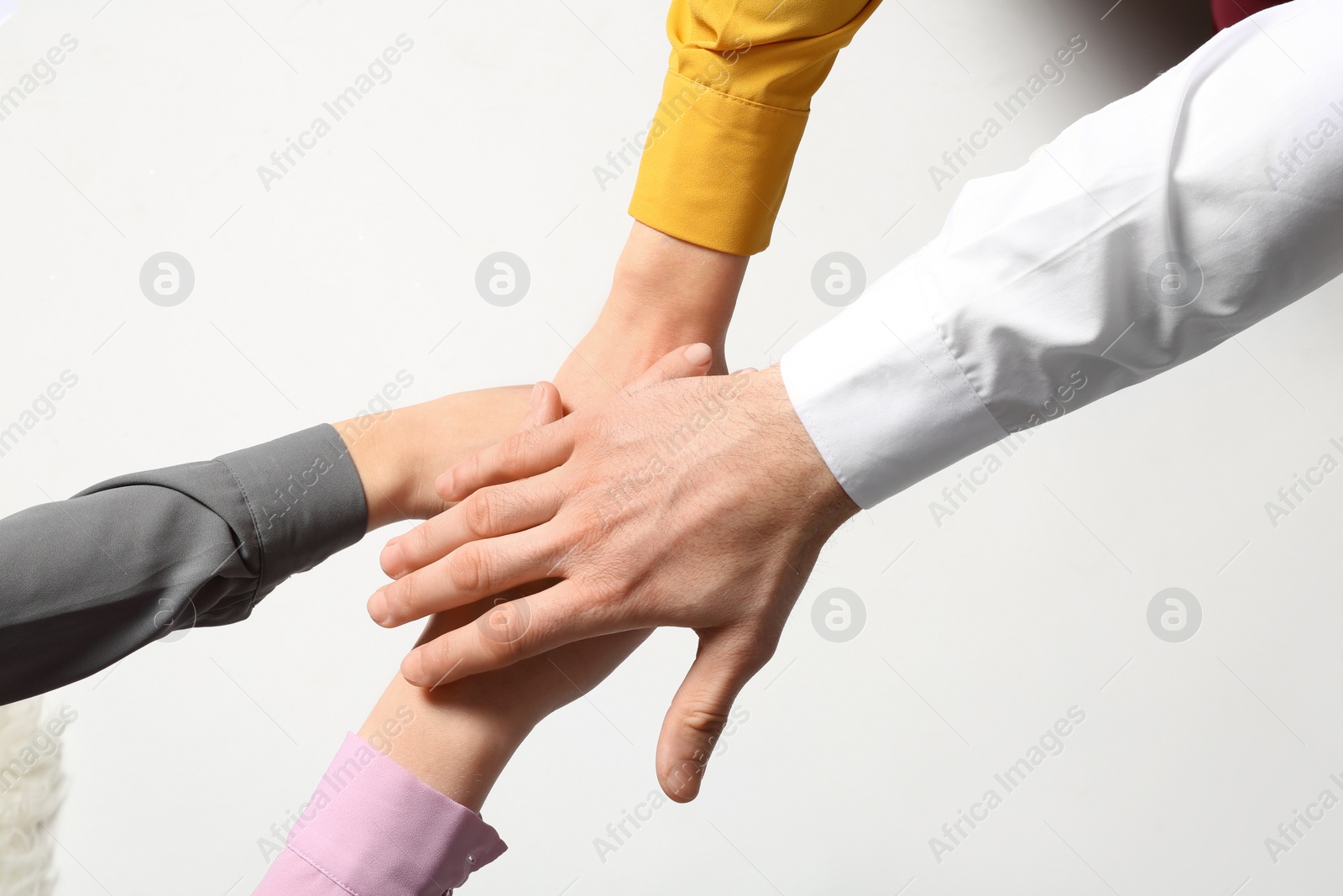 Photo of Young people putting their hands together on white background, top view