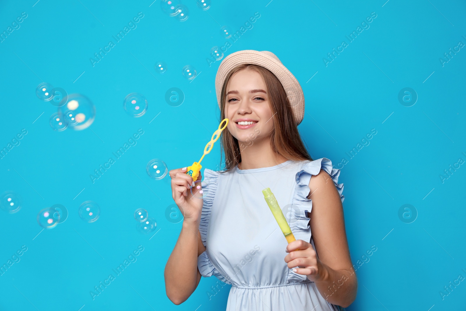 Photo of Young woman blowing soap bubbles on color background