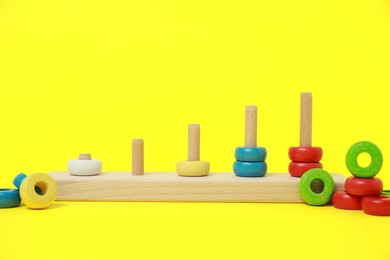 Photo of Stacking and counting game wooden pieces on yellow background. Educational toy for motor skills development