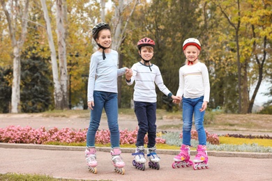 Happy children wearing roller skates in autumn park