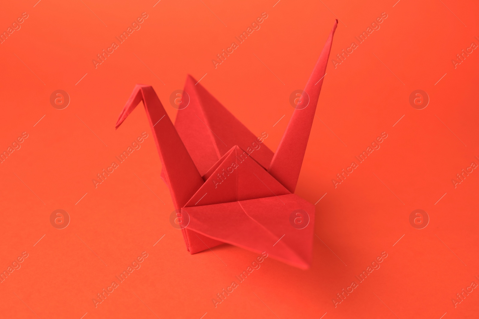 Photo of Origami art. Handmade paper crane on orange background, closeup