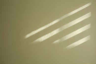 Light and shadow from window on beige wall indoors