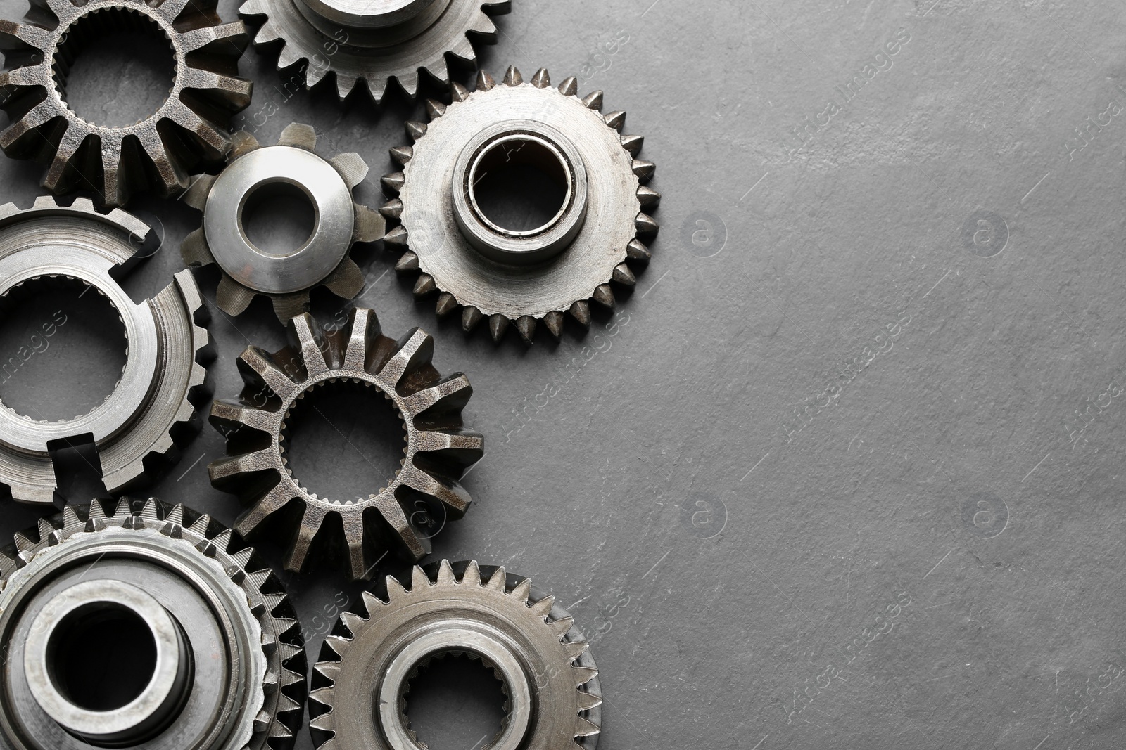 Photo of Different stainless steel gears on light grey background, flat lay. Space for text