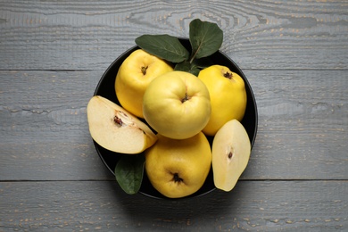 Fresh ripe organic quinces with leaves on grey wooden table, top view