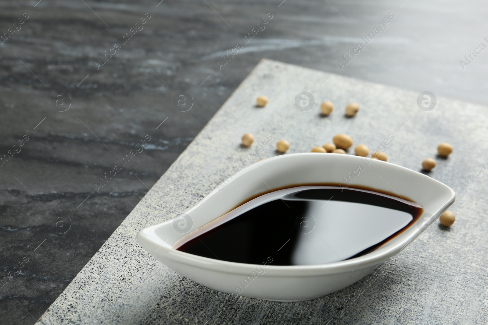 Photo of Board with dish of soy sauce on table