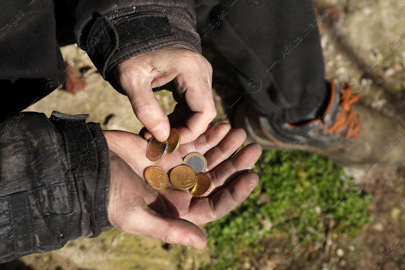 Photo of Poor homeless man holding coins outdoors, closeup