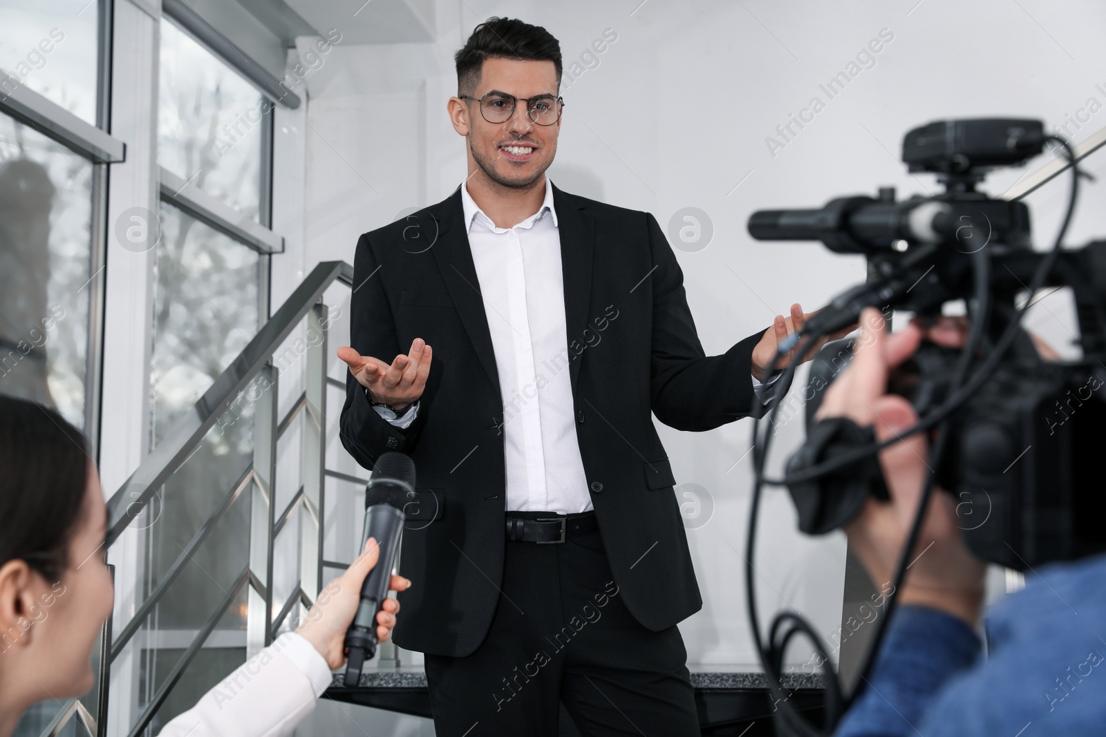 Photo of Happy business man talking to journalists indoors