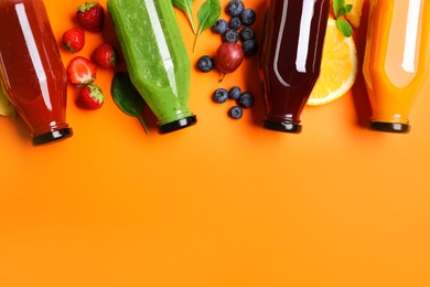 Flat lay composition with bottles of delicious juices and fresh ingredients on orange background. Space for text