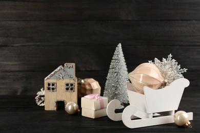 Photo of Beautiful Christmas composition with miniature sleigh on black wooden table. Space for text