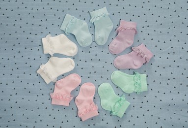 Photo of Many colorful baby socks on light blue fabric, flat lay