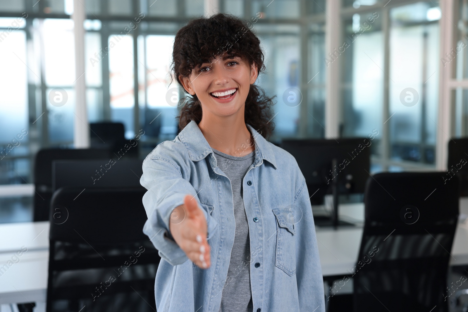 Photo of Happy woman welcoming and offering handshake in office