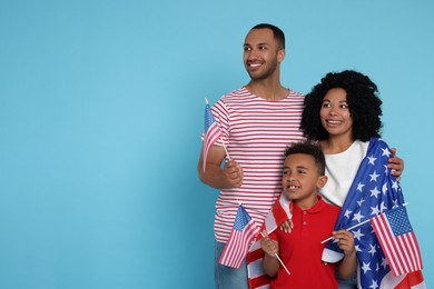 Photo of 4th of July - Independence Day of USA. Happy family with American flags on light blue background, space for text
