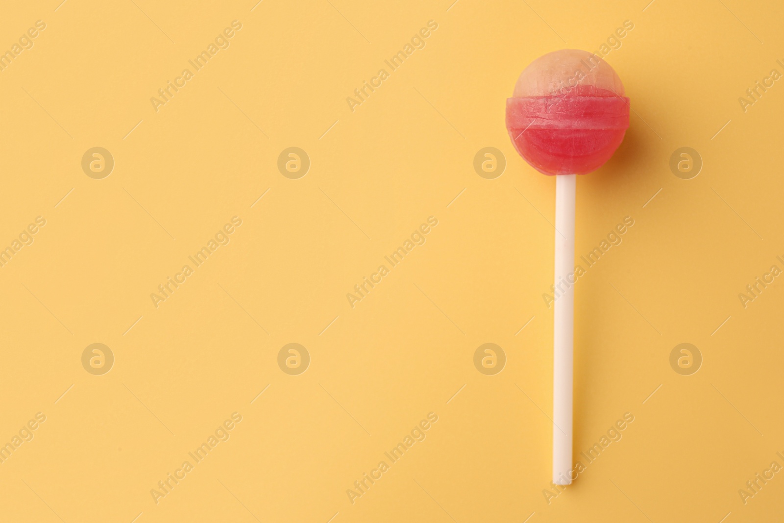 Photo of Tasty lollipop on yellow background, top view. Space for text