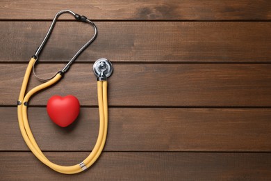 Photo of Stethoscope, red decorative heart and space for text on wooden background, flat lay. Cardiology concept