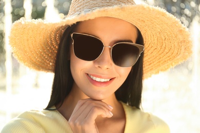 Photo of Beautiful young woman wearing stylish sunglasses outdoors, closeup