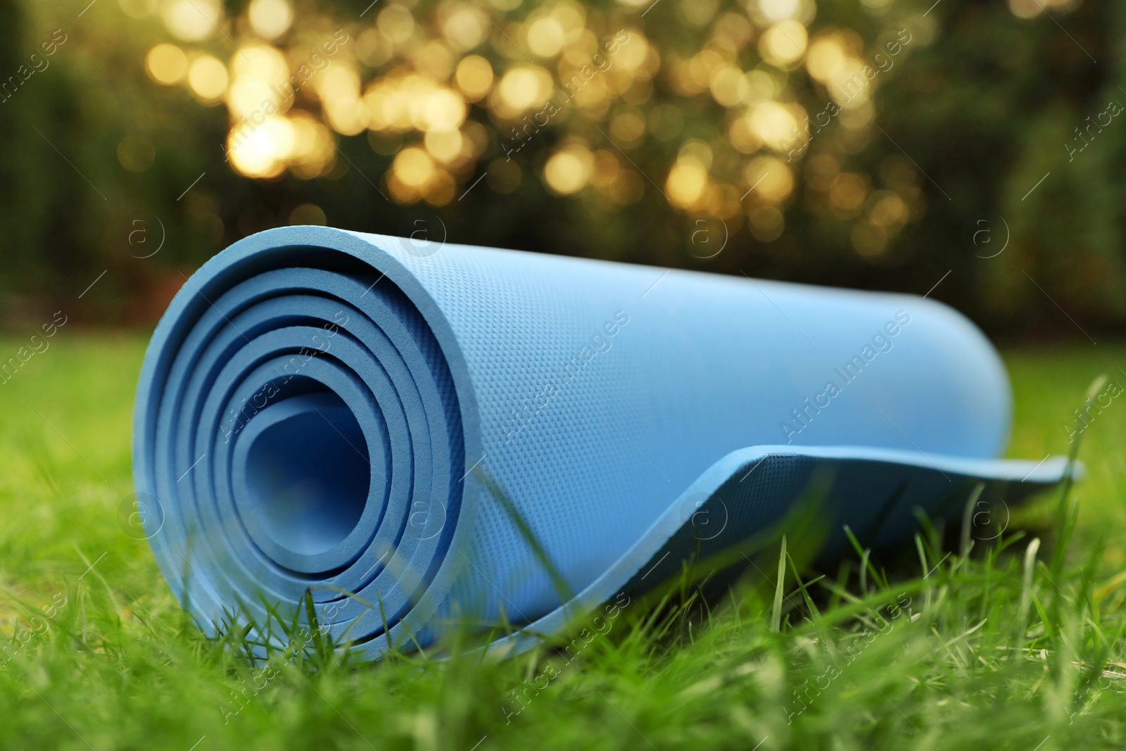Photo of Bright karemat or fitness mat in fresh green grass outdoors, closeup