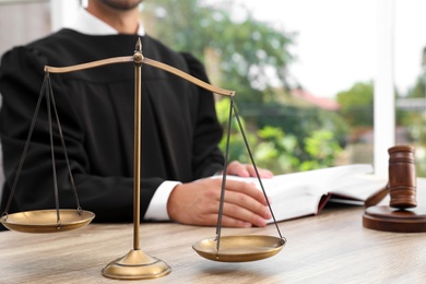 Photo of Scales of justice and blurred judge on background. Criminal law